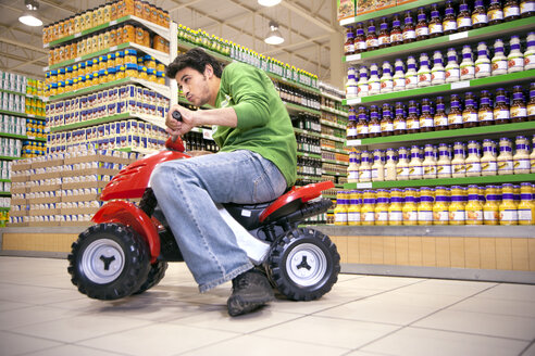 Mann fährt mit Spielzeugauto in einem Supermarkt - RMAF000237