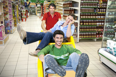 Drei Freunde, die zusammen in einem Supermarkt Spaß haben - RMAF000239