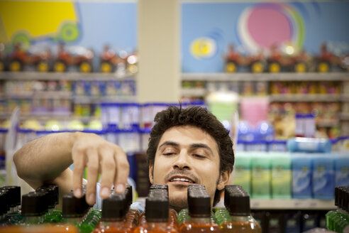 Porträt eines Mannes, der in einem Supermarkt Produkte sucht - RMAF000247