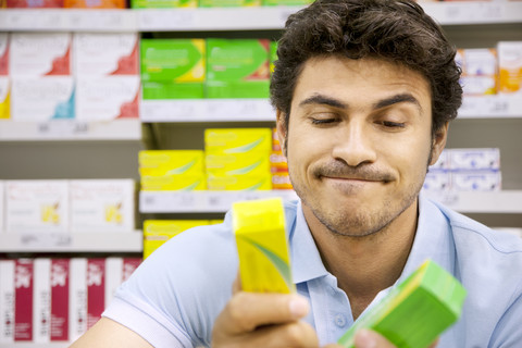 Porträt eines Mannes in einem Supermarkt, der zwei Produkte vergleicht, lizenzfreies Stockfoto