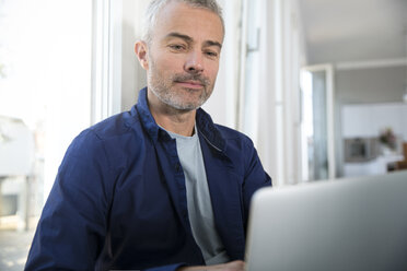 Älterer Mann arbeitet von zu Hause aus mit Laptop - FKF001542