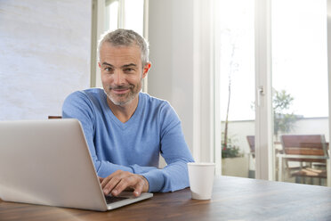 Älterer Mann arbeitet von zu Hause aus mit Laptop - FKF001583