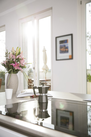 Blumenstrauß und Kaffeemaschine auf dem Ofen im Küchenblock, lizenzfreies Stockfoto
