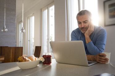 Älterer Mann arbeitet von zu Hause aus mit Laptop - FKF001596