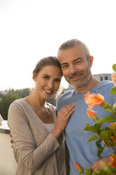 Happy couple standing on balcony, arms around - FKF001601