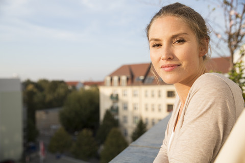 Junge Frau auf Balkon, die die Aussicht genießt, lizenzfreies Stockfoto