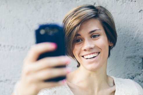 Lächelndes Teenager-Mädchen macht ein Selfie - GIOF000521