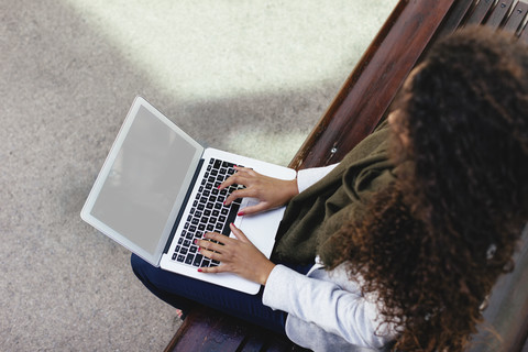 Young woman using laptop on bench stock photo