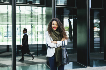 Portrait of confident young businesswoman with businessman in background - EBSF001121