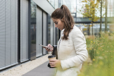 Young businesswoman outdoors looking at cell phone - UUF006056