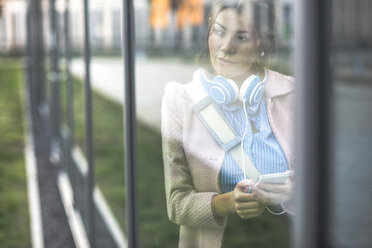 Junge Frau schaut aus dem Fenster - UUF006075