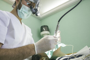 Zahnarzt mit Lupenbrille bei der Behandlung eines Patienten in einer Klinik - ABZF000149