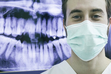 Zahnarzt mit Maske und einer Röntgenaufnahme der Zähne im Hintergrund - ABZF000152