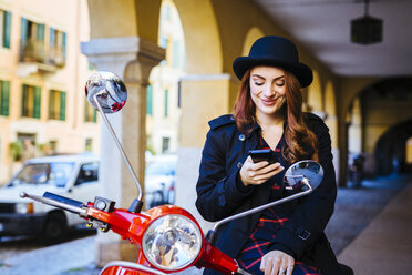 Italy, Verona, young woman with scooter looking at cell phone - GIOF000526