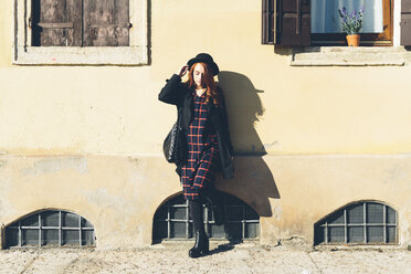 Italy, Verona, young woman leaning against house wall - GIOF000528