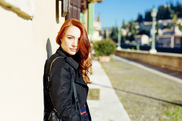 Italy, Verona, portrait of young woman leaning against house wall in sunlight - GIOF000529