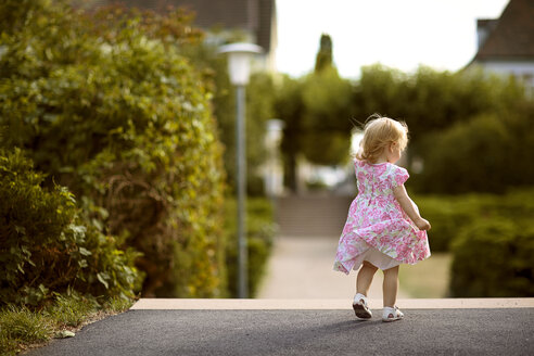 Rückenansicht eines blonden kleinen Mädchens, das ein Kleid mit floralem Muster trägt - NIF000049