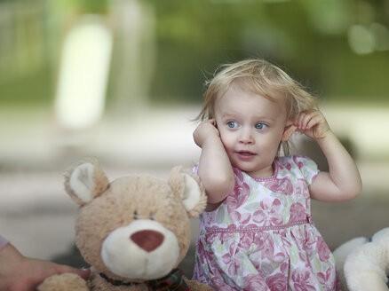 Porträt eines blonden kleinen Mädchens, das neben seinem Teddybär sitzt - NIF000050