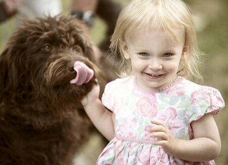 Porträt eines lächelnden blonden kleinen Mädchens mit ihrem Hund - NIF000053