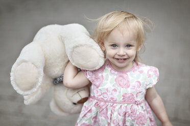 Porträt eines lächelnden blonden kleinen Mädchens mit ihrem Teddybär - NIF000054