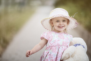 Porträt eines lächelnden blonden kleinen Mädchens mit Hut und Sommerkleid mit Blumenmuster - NIF000055