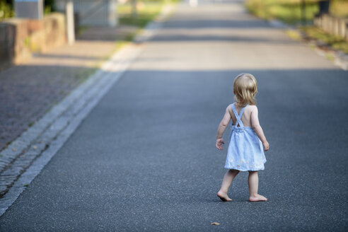 Back view of barefoot blond little girl walking on empty road - NIF000062