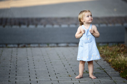 Barefoot blond little girl standing on pavement looking up - NIF000064