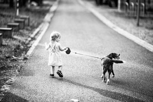 Back view of little girl walking along the street with her dog - NIF000067