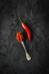 Spoon of homemade chili paste and chili pod on black ground - EVGF002506