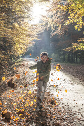 Boy playing with leaves in autumnal forest - DEGF000588