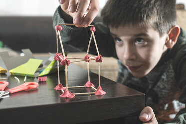 Boy building a house with modeling clay and toothpicks - DEGF000599