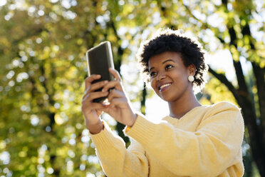 Schöne schwarze Frau mit Smartphone, draußen im Herbst - MAUF000006