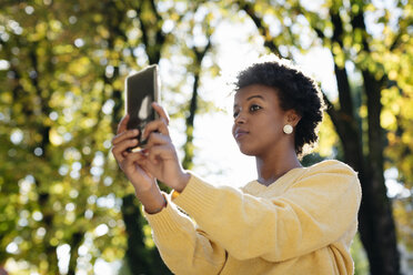 Schöne schwarze Frau mit Smartphone, draußen im Herbst - MAUF000008