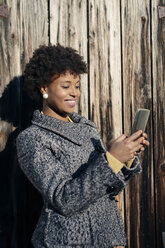 Schöne schwarze Frau mit Smartphone, draußen im Herbst - MAUF000013
