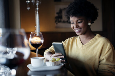 Schöne schwarze Frau mit Smartphone im Restaurant - MAUF000017