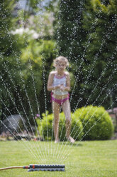 Mädchen hinter Sprinkleranlage im Garten - PAF001467