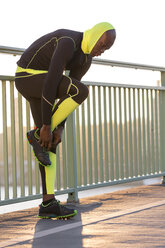 Athlete tying his shoes on bridge - MADF000612