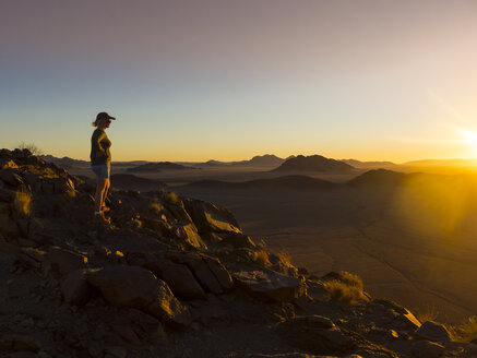 Afrika, Namibia, Hardap, Hammerstein, Kulala Wilderness Reserve, Tsaris Mountains, Frau steht in der Namib-Wüste bei Sonnenuntergang - AMF004422