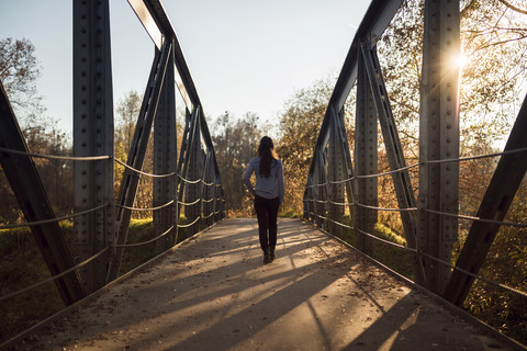 Rückenansicht einer Frau auf einer Brücke in der Abenddämmerung, lizenzfreies Stockfoto