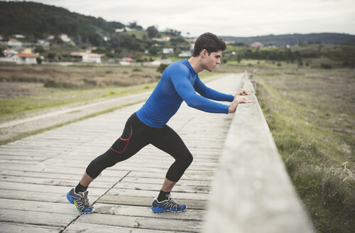 Spanien, Ferrol, Jogger, der sich auf einer Promenade dehnt - RAEF000668