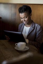 Young woman sitting in a cafe using digital tablet - MAUF000019