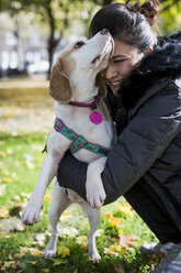 Woman cuddling her dog on a meadow - MAUF000047