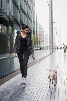 UK, London, Frau und ihr Hund gehen auf dem Bürgersteig in der Stadt spazieren - MAUF000051