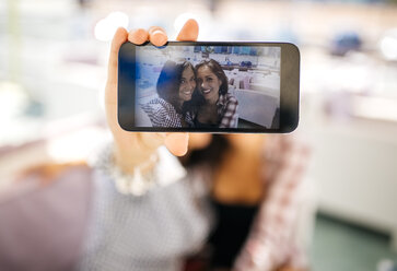 Selfie of two smiling female friends on cell phone display - MGOF001069