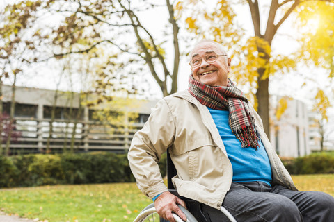 Smiling senior man in wheelchair outdoors stock photo