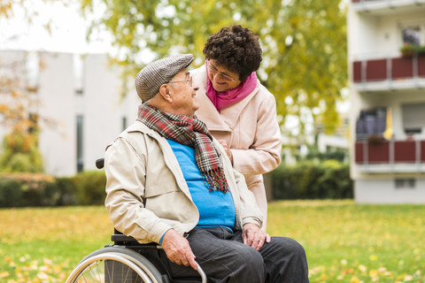 Ältere Frau sieht ihren Mann im Rollstuhl an, lizenzfreies Stockfoto