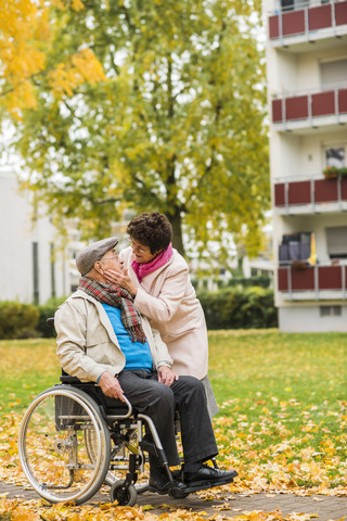 Ältere Frau sieht ihren Mann im Rollstuhl an, lizenzfreies Stockfoto