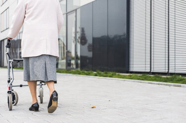 Ältere Frau geht mit Rollator auf dem Bürgersteig - UUF006131