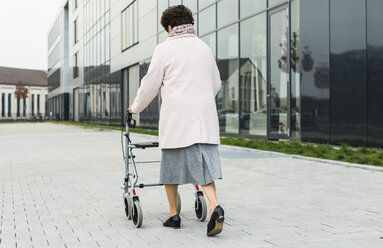 Ältere Frau geht mit Rollator auf dem Bürgersteig - UUF006134