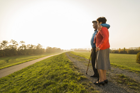 Älteres Paar mit Wanderstöcken in der Natur stehend, lizenzfreies Stockfoto